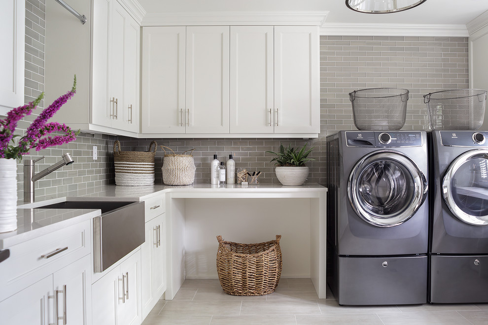 Idéer för att renovera en stor vintage vita u-formad vitt tvättstuga enbart för tvätt, med en allbänk, skåp i shakerstil, vita skåp, bänkskiva i kvarts, grå väggar, klinkergolv i keramik, en tvättmaskin och torktumlare bredvid varandra och grått golv