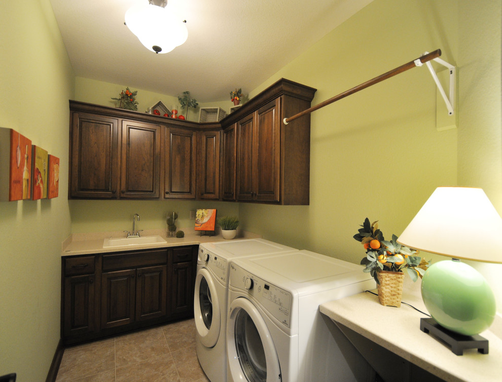 ミルウォーキーにある広いトラディショナルスタイルのおしゃれな洗濯室 (ll型、ドロップインシンク、レイズドパネル扉のキャビネット、濃色木目調キャビネット、珪岩カウンター、緑の壁、セラミックタイルの床、左右配置の洗濯機・乾燥機) の写真