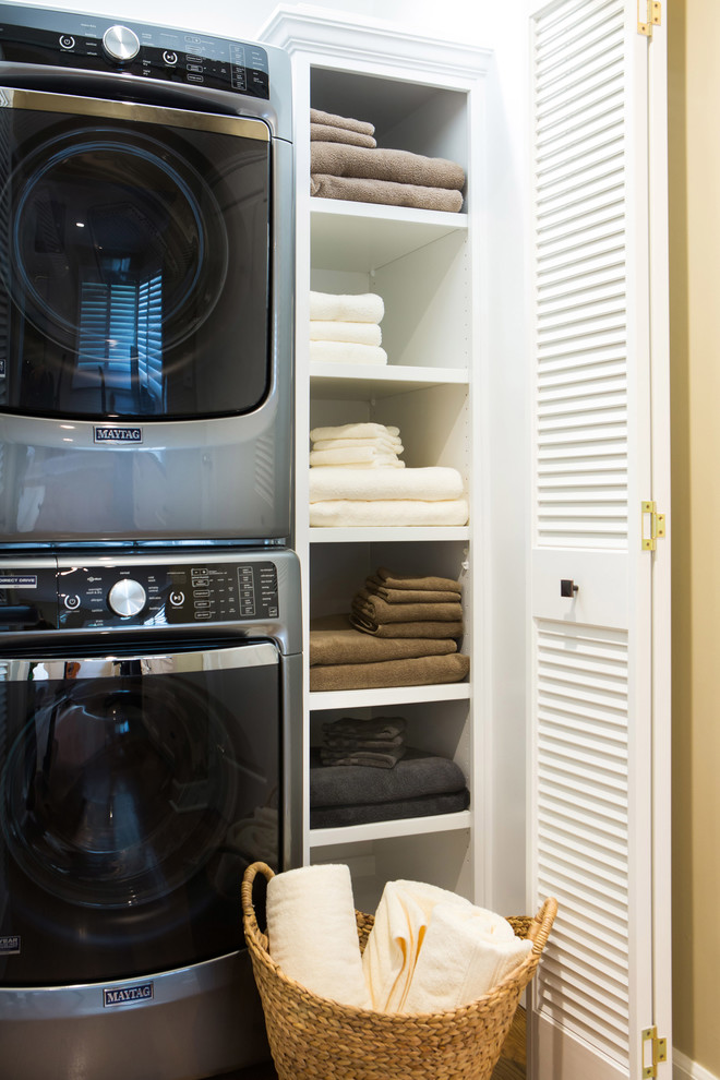 Imagen de armario lavadero lineal clásico renovado pequeño con armarios abiertos, puertas de armario blancas, paredes blancas, suelo de madera en tonos medios y lavadora y secadora apiladas