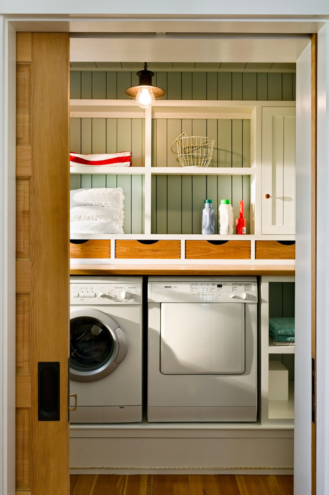 This is an example of a beach style utility room in Portland Maine with a side by side washer and dryer.