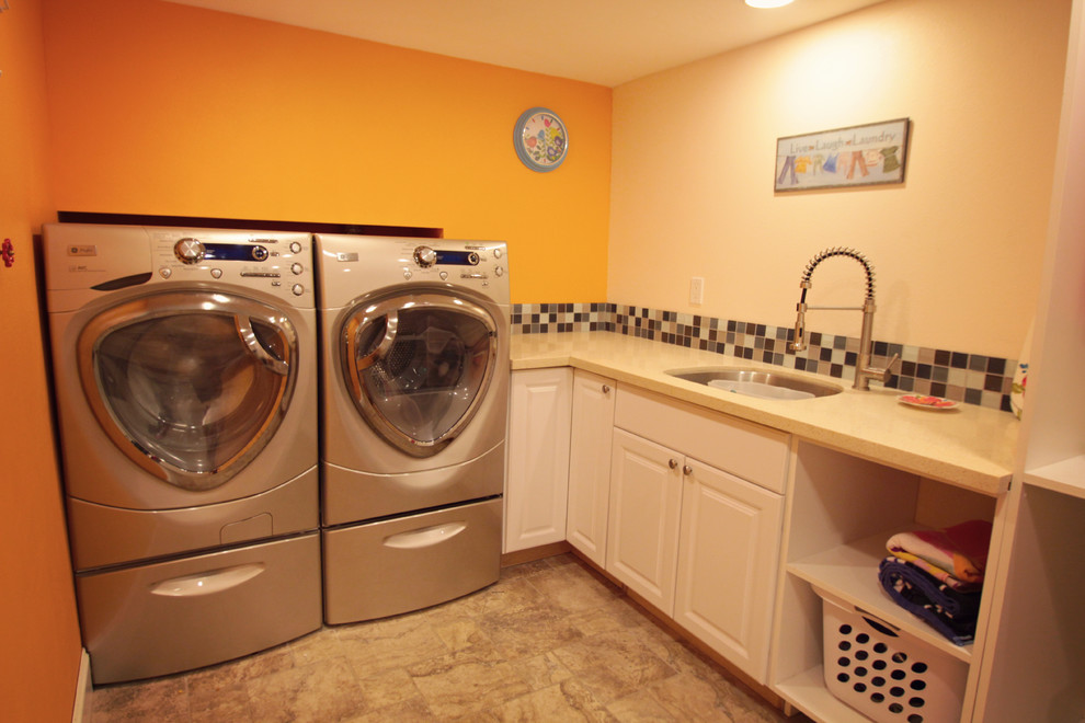 Exempel på en mellanstor modern l-formad tvättstuga enbart för tvätt, med en undermonterad diskho, luckor med upphöjd panel, vita skåp, orange väggar, en tvättmaskin och torktumlare bredvid varandra, bänkskiva i kvarts och klinkergolv i keramik