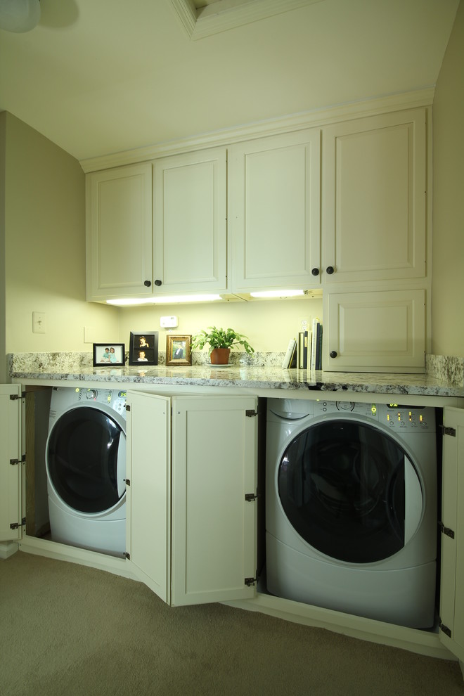 Imagen de lavadero multiusos y lineal clásico con armarios con paneles con relieve, puertas de armario blancas, moqueta, lavadora y secadora escondidas y paredes grises