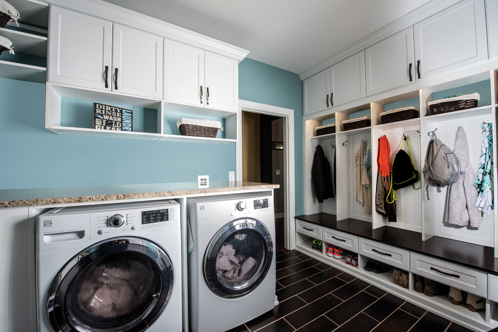 Design ideas for a large contemporary l-shaped utility room in Minneapolis with recessed-panel cabinets, white cabinets, blue walls, ceramic flooring, a side by side washer and dryer, brown floors and black worktops.