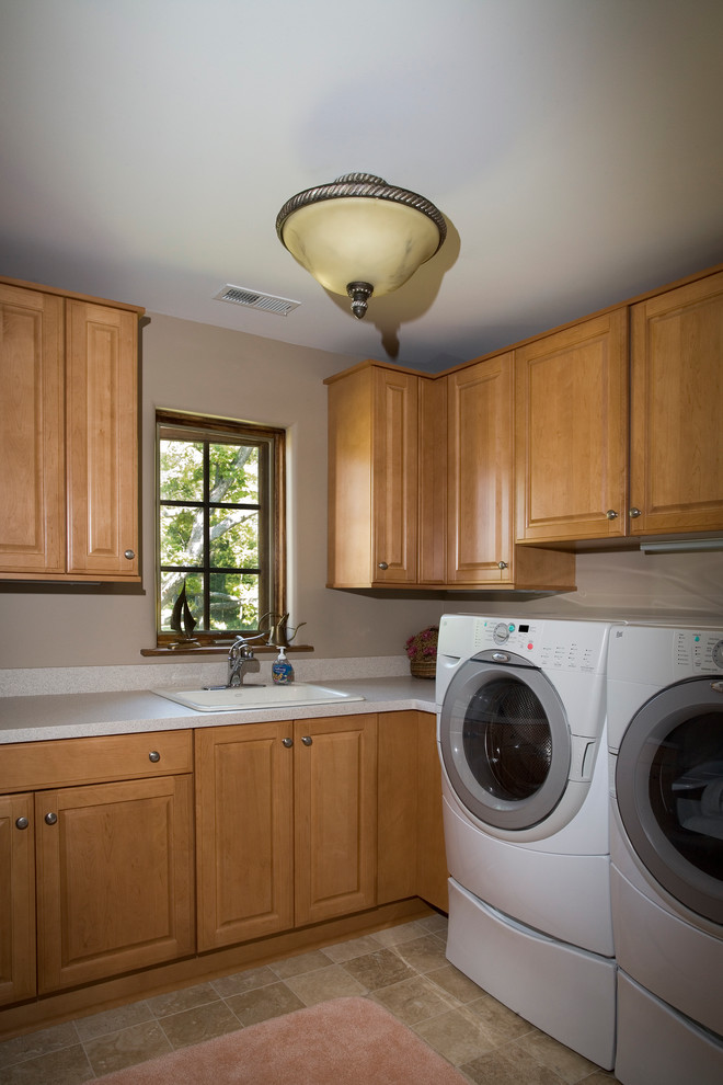 Large classic u-shaped separated utility room in Chicago with a built-in sink, raised-panel cabinets, dark wood cabinets, composite countertops, beige walls, limestone flooring and a side by side washer and dryer.