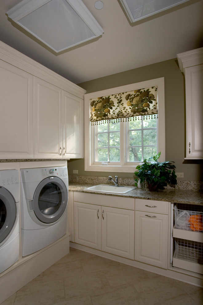 Inredning av en klassisk mycket stor u-formad tvättstuga enbart för tvätt, med en nedsänkt diskho, luckor med upphöjd panel, vita skåp, bänkskiva i koppar, gröna väggar, klinkergolv i porslin och en tvättmaskin och torktumlare bredvid varandra