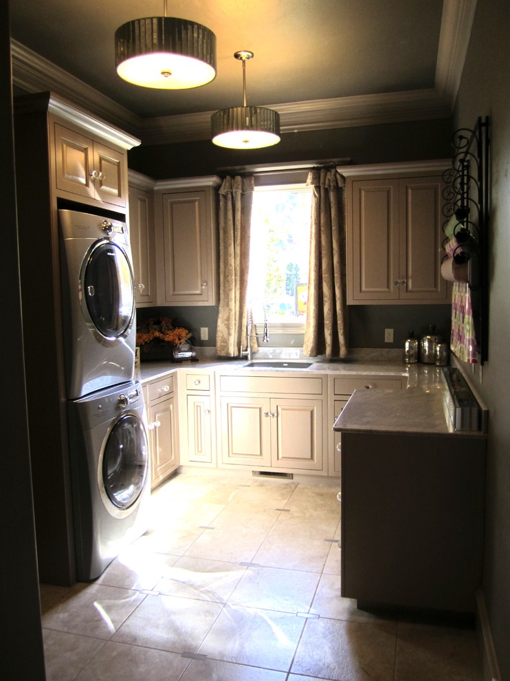 Example of a large classic u-shaped ceramic tile utility room design in Oklahoma City with an undermount sink, raised-panel cabinets and a stacked washer/dryer