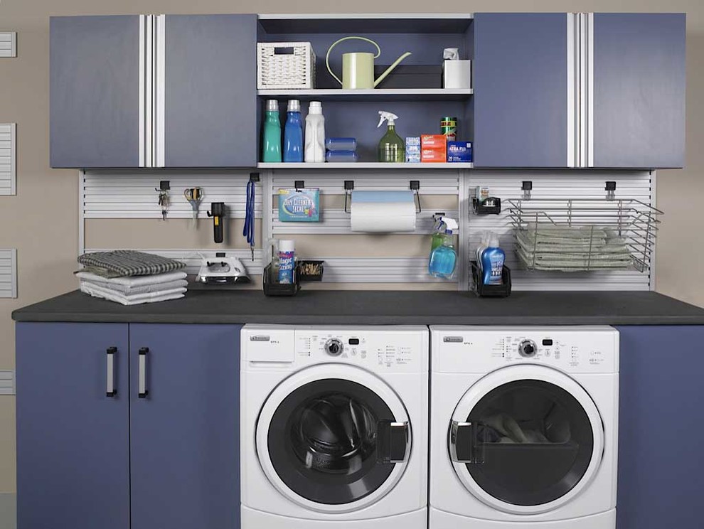 Exempel på en mellanstor modern linjär tvättstuga enbart för tvätt, med släta luckor, blå skåp, bänkskiva i kvarts, beige väggar och en tvättmaskin och torktumlare bredvid varandra