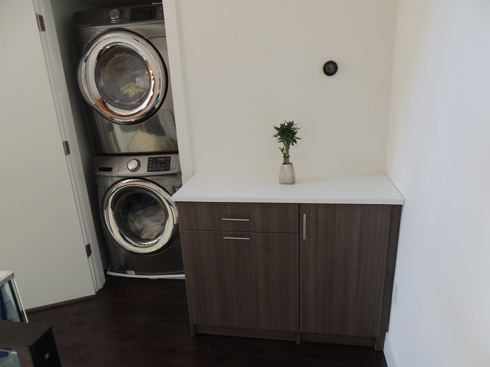 Immagine di una piccola lavanderia multiuso minimal con ante lisce, ante in legno scuro e top in superficie solida