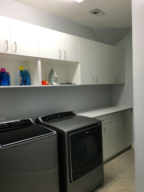 Large elegant single-wall linoleum floor utility room photo in St Louis with flat-panel cabinets, white cabinets, laminate countertops and a side-by-side washer/dryer