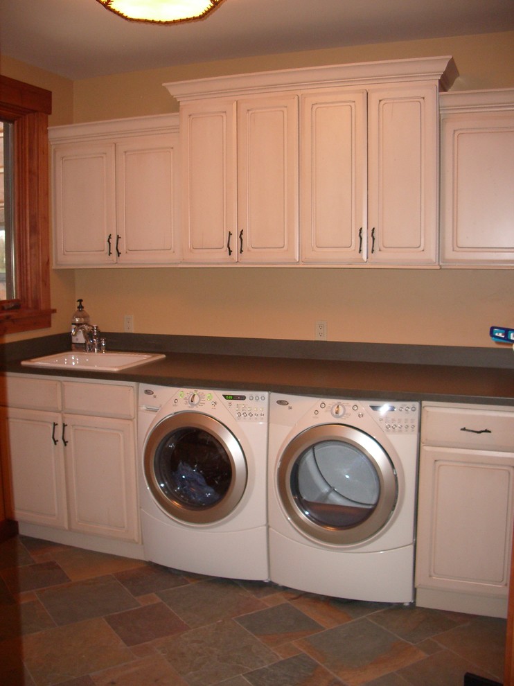 Foto di una lavanderia classica con ante con bugna sagomata, ante beige e top in superficie solida