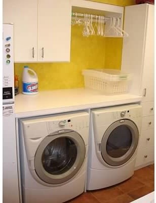 Esempio di una piccola sala lavanderia con ante lisce, ante bianche, top in laminato, pareti gialle, pavimento in vinile e lavatrice e asciugatrice affiancate