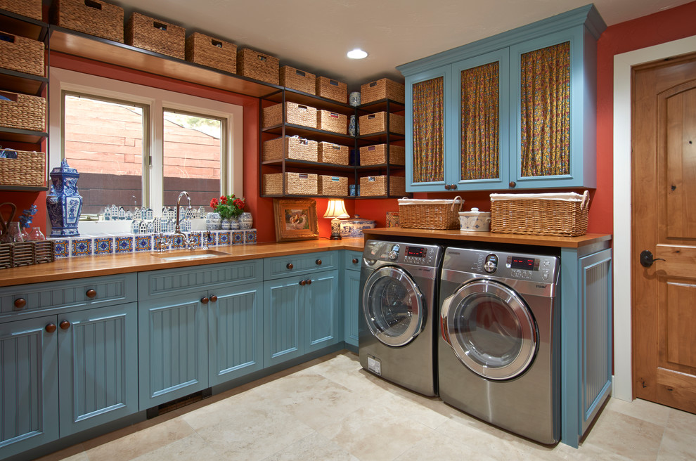 Idee per una grande sala lavanderia con ante blu, pareti rosse, lavello sottopiano, top in legno, pavimento in gres porcellanato, lavatrice e asciugatrice affiancate e pavimento beige