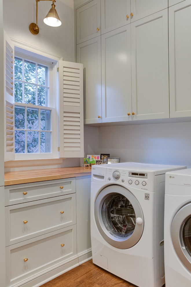 Dedicated laundry room - transitional l-shaped medium tone wood floor and brown floor dedicated laundry room idea in Other with recessed-panel cabinets, gray cabinets, wood countertops, white walls, a side-by-side washer/dryer and brown countertops