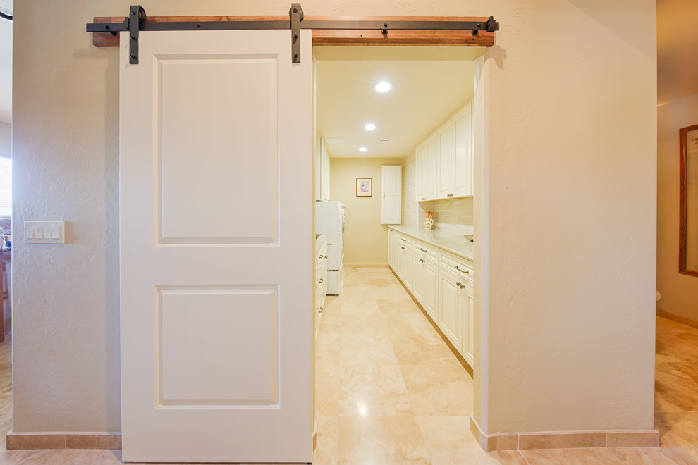 Inspiration for a large traditional galley separated utility room in Phoenix with a submerged sink, raised-panel cabinets, white cabinets, quartz worktops, beige walls, travertine flooring, a side by side washer and dryer and beige floors.