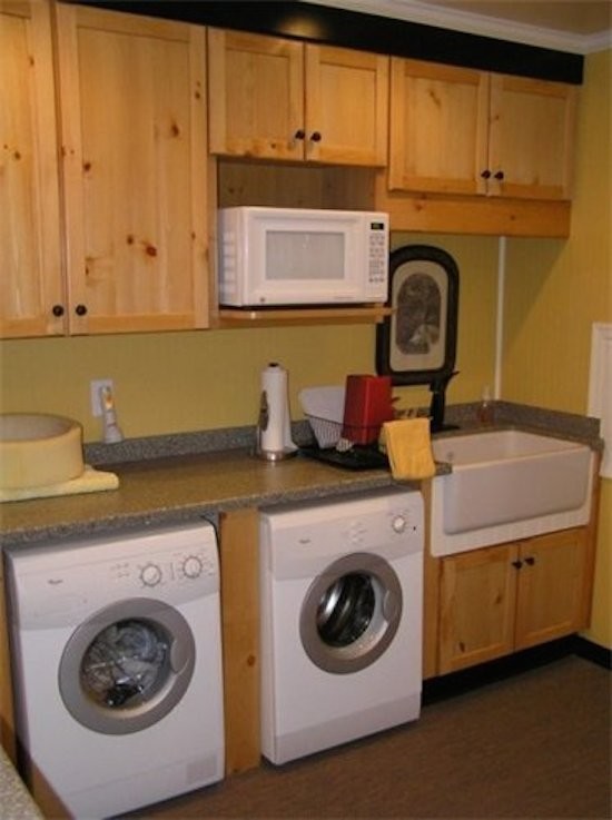 リッチモンドにあるおしゃれなランドリールーム (エプロンフロントシンク、落し込みパネル扉のキャビネット、淡色木目調キャビネット、黄色い壁、左右配置の洗濯機・乾燥機) の写真