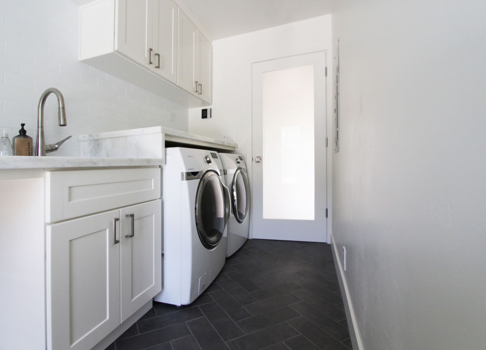 Idéer för små parallella grått tvättstugor enbart för tvätt, med en undermonterad diskho, skåp i shakerstil, vita skåp, bänkskiva i kvartsit, vita väggar, klinkergolv i porslin, en tvättmaskin och torktumlare bredvid varandra och svart golv