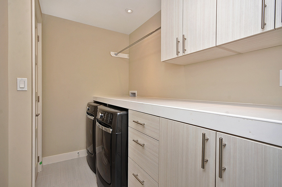 Design ideas for a small contemporary single-wall separated utility room in Ottawa with flat-panel cabinets, light wood cabinets, tile countertops, beige walls, laminate floors, a side by side washer and dryer, beige floors and white worktops.