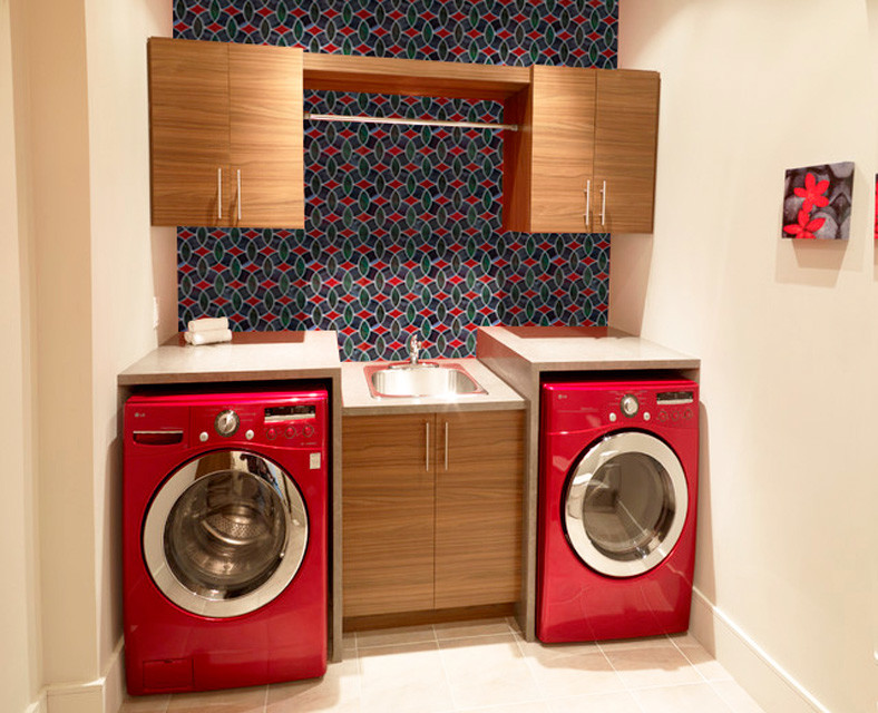 ゴールドコーストにある中くらいなモダンスタイルのおしゃれな洗濯室 (シングルシンク、茶色いキャビネット、コの字型、テラゾーカウンター、磁器タイルの床、上下配置の洗濯機・乾燥機、ベージュの床、ベージュのキッチンカウンター、インセット扉のキャビネット、赤い壁) の写真