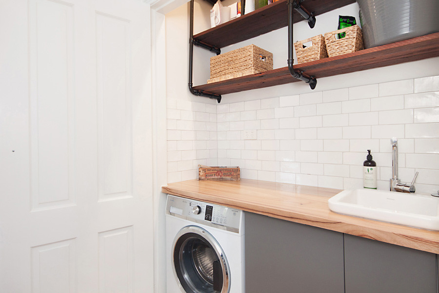 Design ideas for a small modern single-wall utility room in Newcastle - Maitland with flat-panel cabinets, grey cabinets, wood worktops, white walls, a belfast sink, medium hardwood flooring and an integrated washer and dryer.