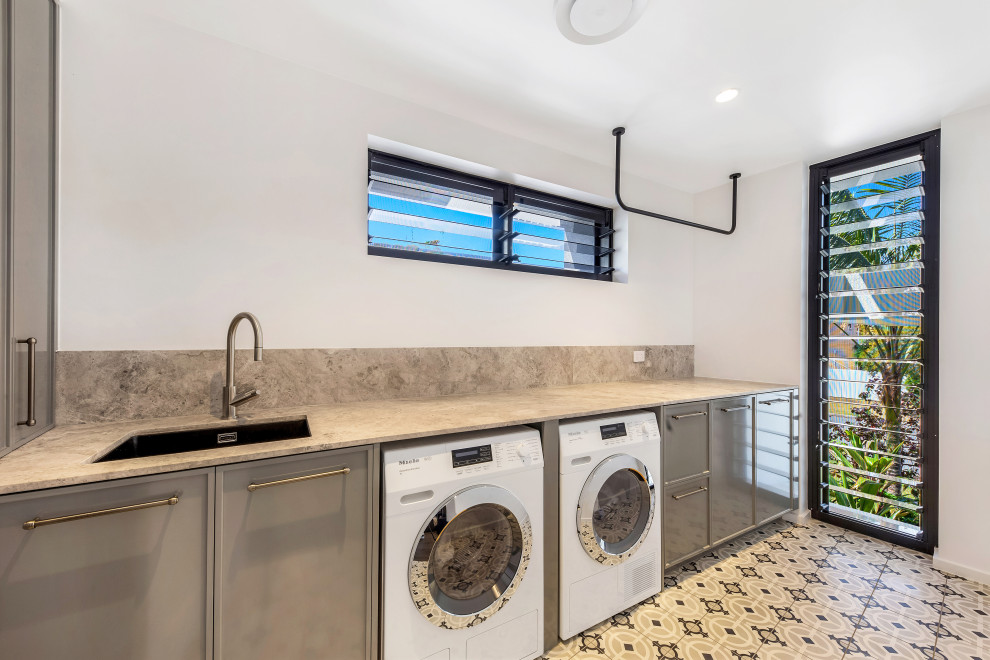 Idee per una sala lavanderia design con top in marmo, paraspruzzi grigio, paraspruzzi in marmo, pareti bianche e lavatrice e asciugatrice affiancate