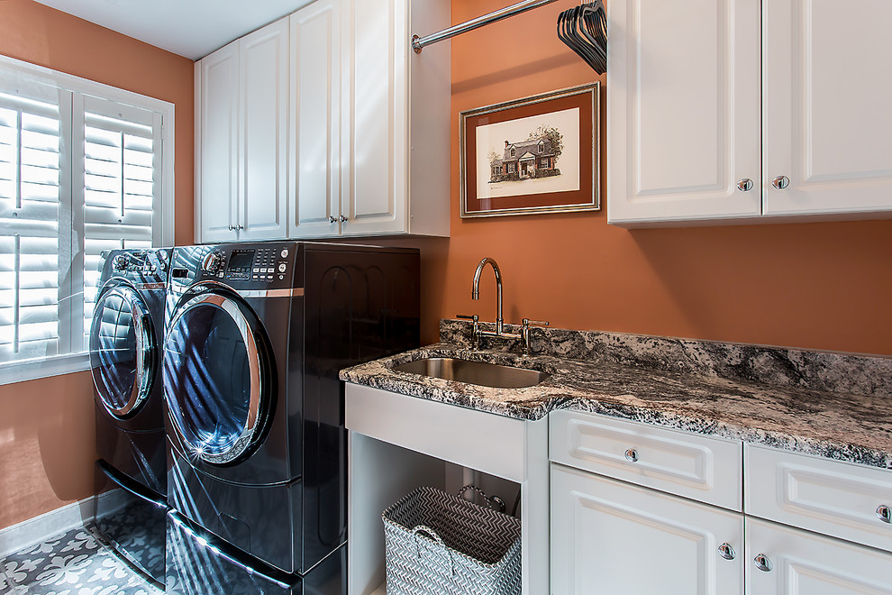 Inspiration för små klassiska linjära tvättstugor enbart för tvätt, med en undermonterad diskho, vita skåp, granitbänkskiva, orange väggar, klinkergolv i porslin, en tvättmaskin och torktumlare bredvid varandra och luckor med upphöjd panel