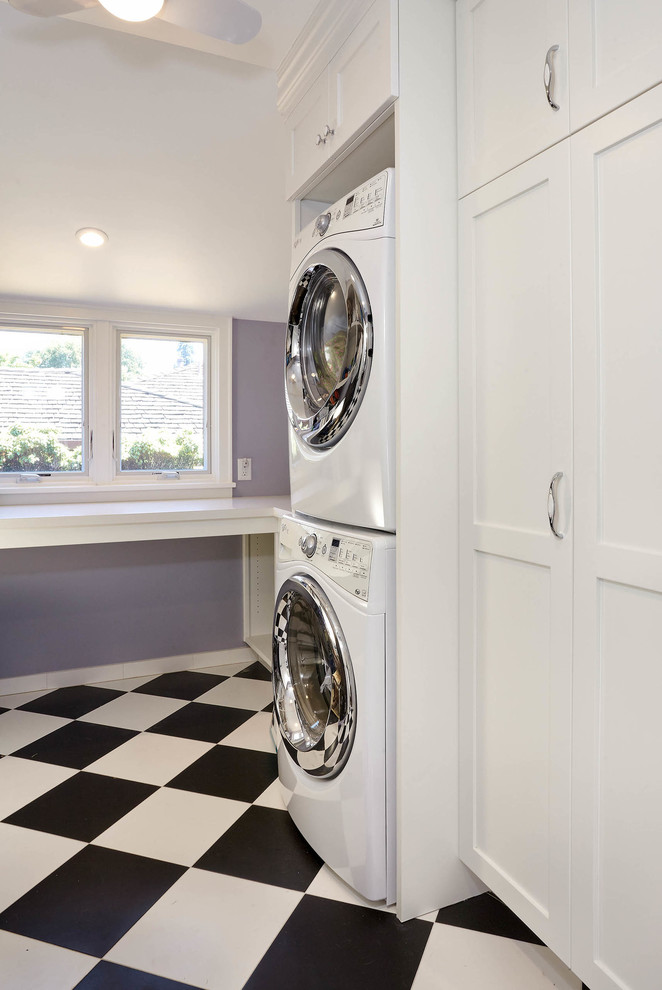 Inredning av en klassisk mellanstor u-formad tvättstuga enbart för tvätt, med en undermonterad diskho, skåp i shakerstil, vita skåp, bänkskiva i kvarts, lila väggar, klinkergolv i keramik, en tvättpelare och svart golv