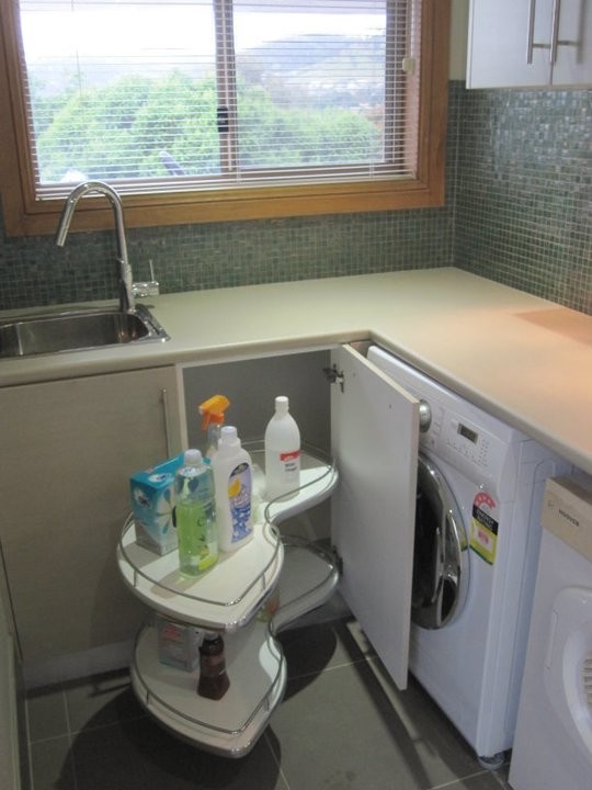 Foto på en liten funkis l-formad tvättstuga enbart för tvätt, med en enkel diskho, laminatbänkskiva, vita väggar, klinkergolv i porslin och en tvättmaskin och torktumlare bredvid varandra