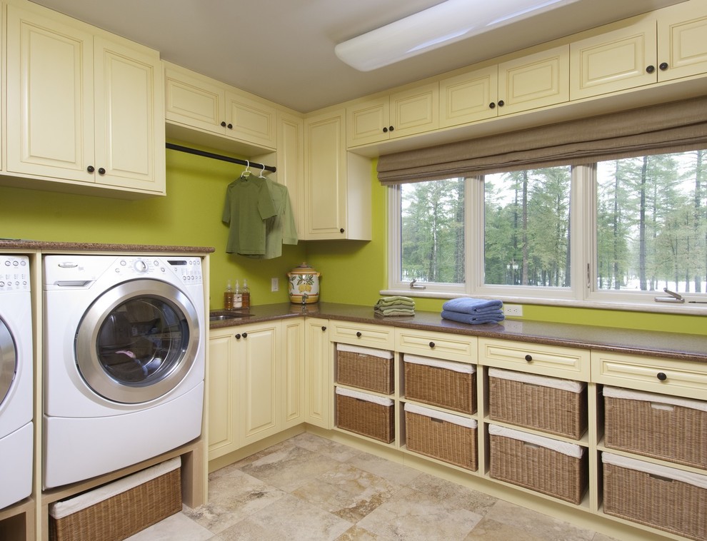 Foto di una lavanderia chic di medie dimensioni con lavello sottopiano, ante con bugna sagomata, ante beige, pareti verdi, lavatrice e asciugatrice affiancate e pavimento marrone