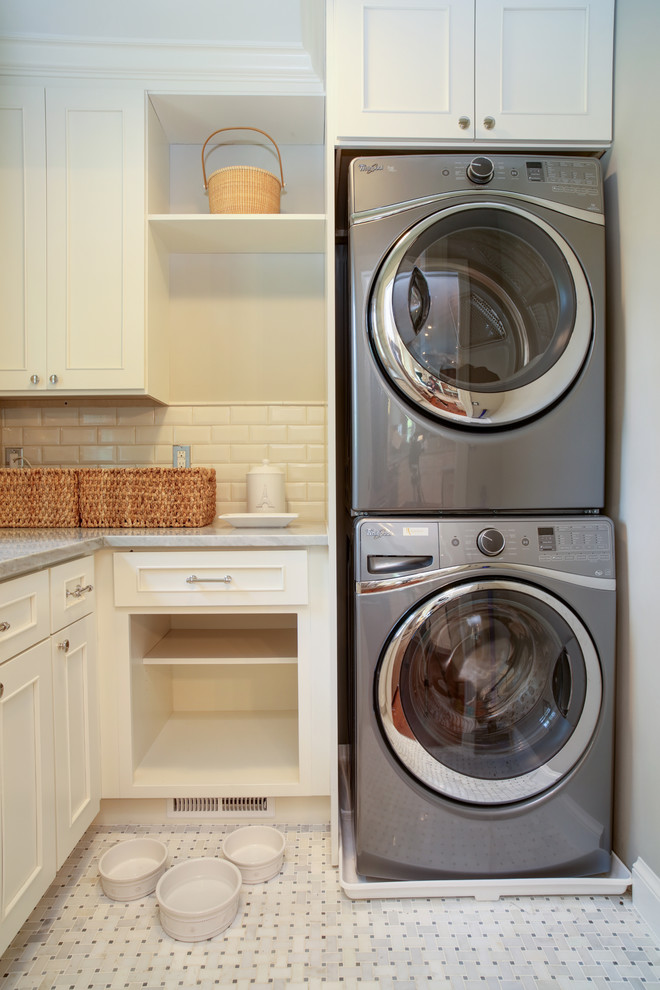 Kleine Klassische Waschküche in L-Form mit weißen Schränken, Marmor-Arbeitsplatte und Waschmaschine und Trockner gestapelt in Washington, D.C.