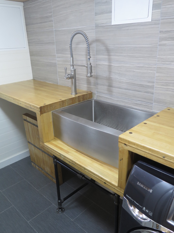 Inspiration for a small industrial galley separated utility room in New York with a belfast sink, wood worktops, white walls, porcelain flooring and a side by side washer and dryer.