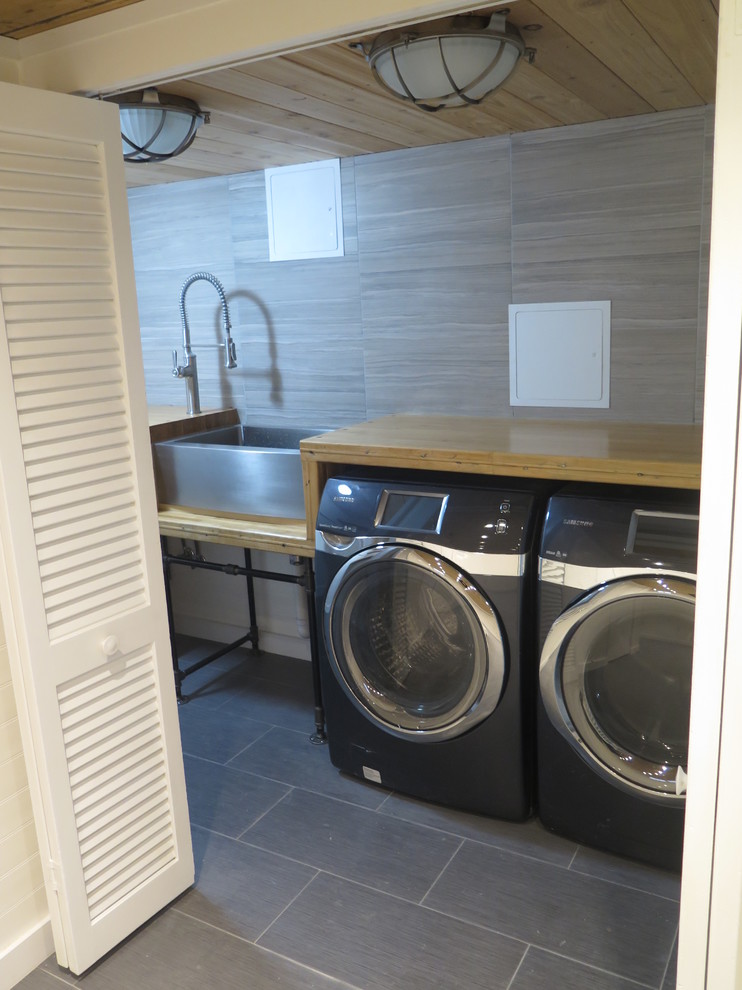 Bild på en liten industriell parallell tvättstuga enbart för tvätt, med en rustik diskho, träbänkskiva, vita väggar, klinkergolv i porslin och en tvättmaskin och torktumlare bredvid varandra