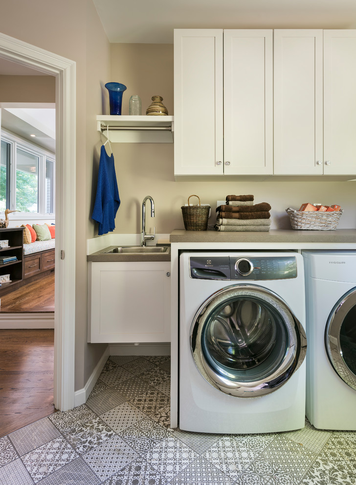 Inspiration för små klassiska linjära grått tvättstugor enbart för tvätt, med en nedsänkt diskho, skåp i shakerstil, vita skåp, bänkskiva i kvarts, beige väggar, en tvättmaskin och torktumlare bredvid varandra och flerfärgat golv