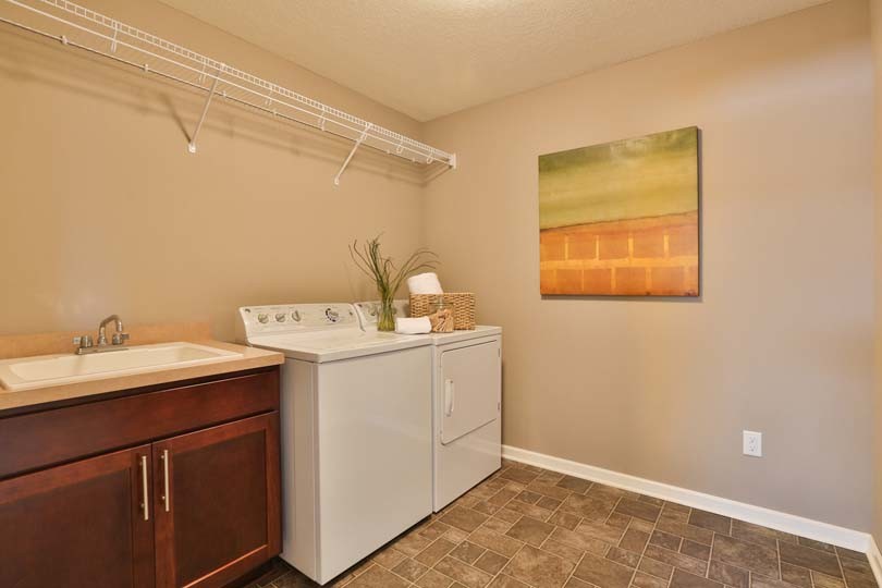 Inspiration for a mid-sized timeless single-wall ceramic tile dedicated laundry room remodel in Minneapolis with a drop-in sink, laminate countertops, beige walls and a side-by-side washer/dryer