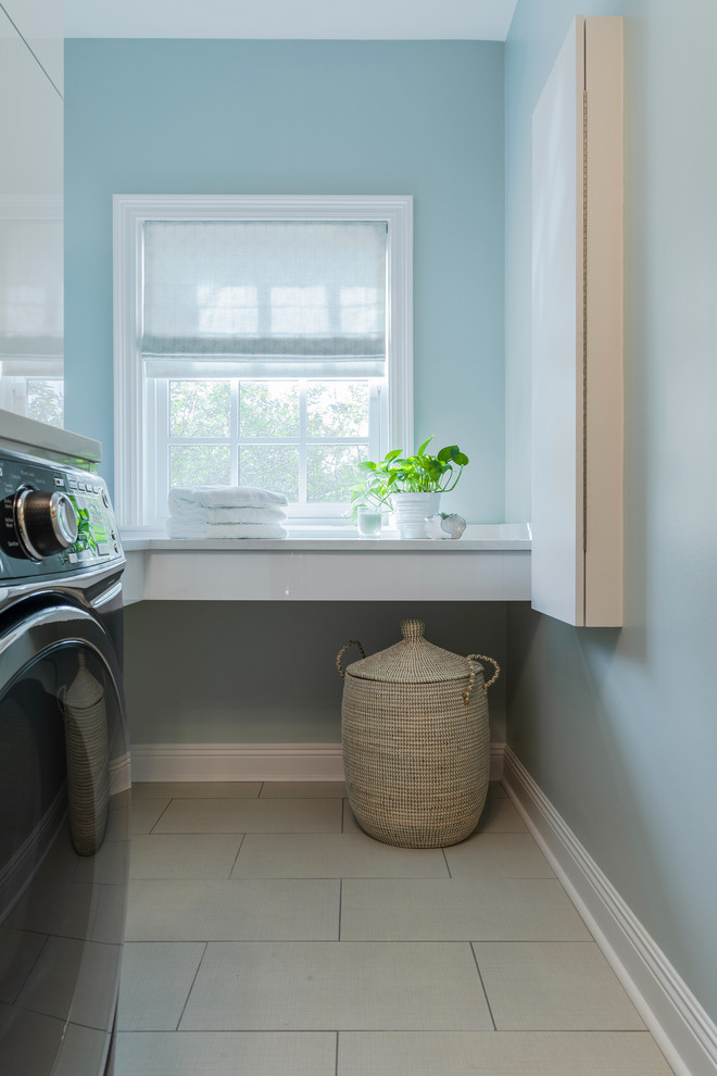 ニューオリンズにある高級な中くらいなトランジショナルスタイルのおしゃれな洗濯室 (アンダーカウンターシンク、フラットパネル扉のキャビネット、白いキャビネット、珪岩カウンター、セラミックタイルの床、左右配置の洗濯機・乾燥機、ベージュの床、白いキッチンカウンター、L型、青い壁) の写真