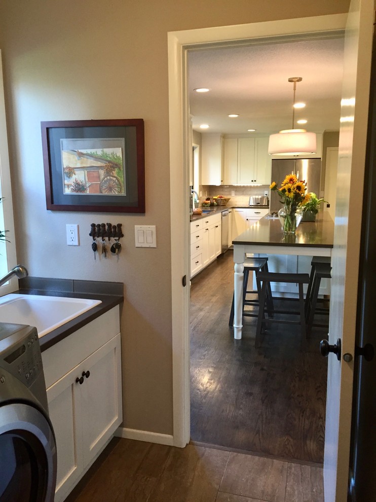 Photo of a small traditional single-wall utility room in Portland with a single-bowl sink, shaker cabinets, white cabinets, granite worktops, beige walls, porcelain flooring, a side by side washer and dryer, beige floors and black worktops.