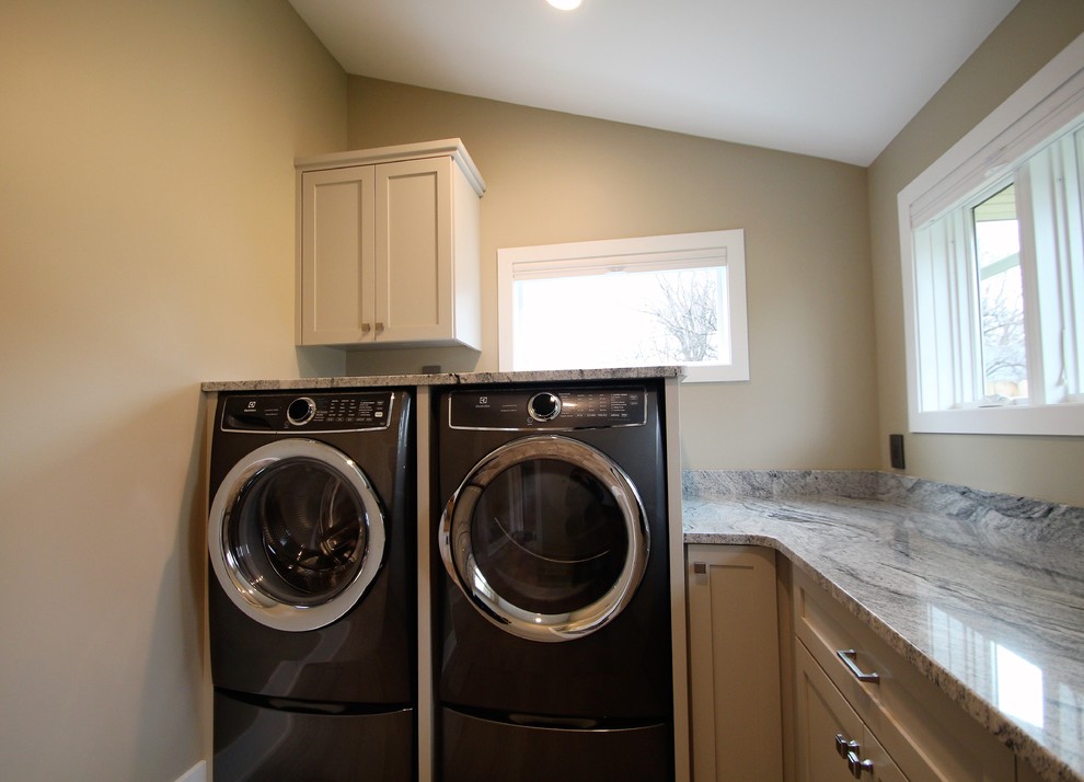 Idéer för att renovera en stor vintage flerfärgade l-formad flerfärgat tvättstuga enbart för tvätt, med en undermonterad diskho, skåp i shakerstil, vita skåp, granitbänkskiva, klinkergolv i porslin, en tvättmaskin och torktumlare bredvid varandra, grått golv och beige väggar