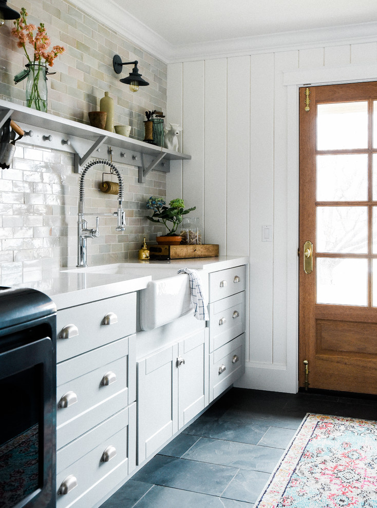Foto på en stor lantlig vita tvättstuga, med en rustik diskho, skåp i shakerstil, grå skåp, bänkskiva i kvartsit och en tvättmaskin och torktumlare bredvid varandra
