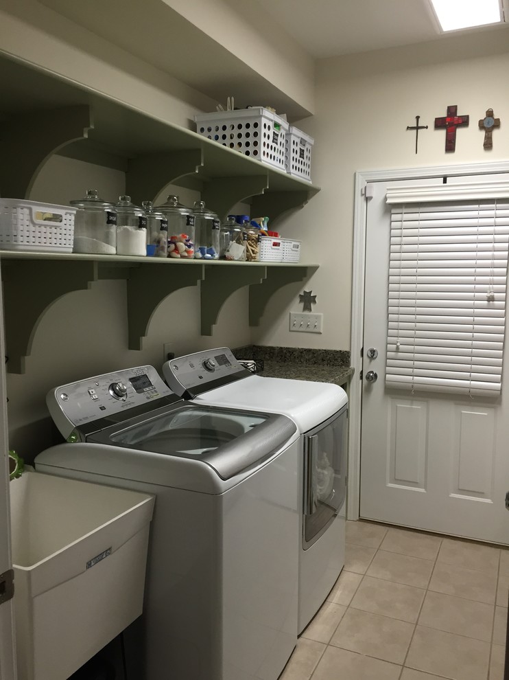 Immagine di una piccola sala lavanderia tradizionale con lavatoio, ante verdi, top in granito, pareti bianche, pavimento con piastrelle in ceramica, lavatrice e asciugatrice affiancate e nessun'anta
