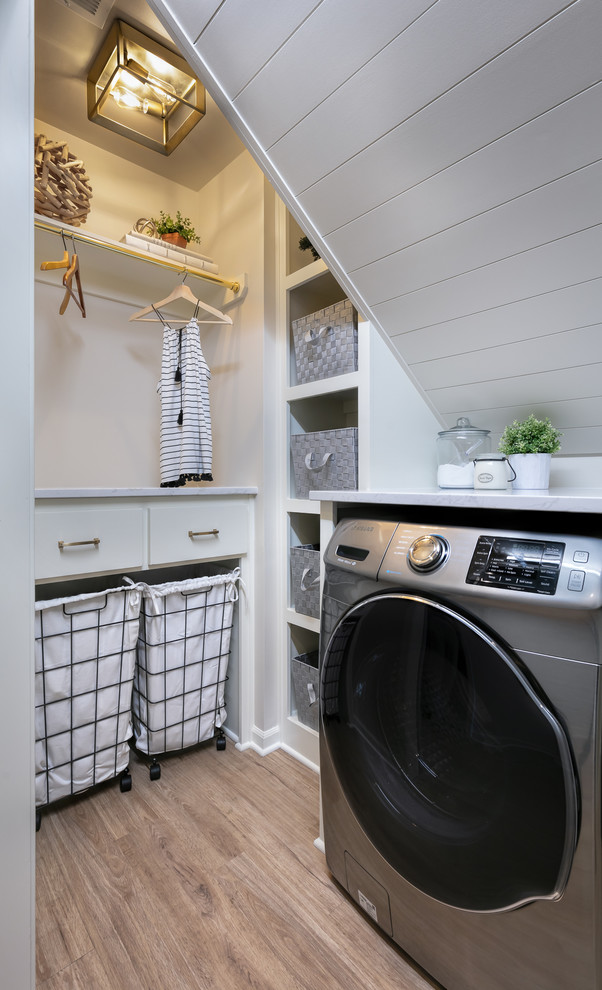 Lantlig inredning av en vita vitt tvättstuga enbart för tvätt, med öppna hyllor, vita skåp, vita väggar, mellanmörkt trägolv och brunt golv
