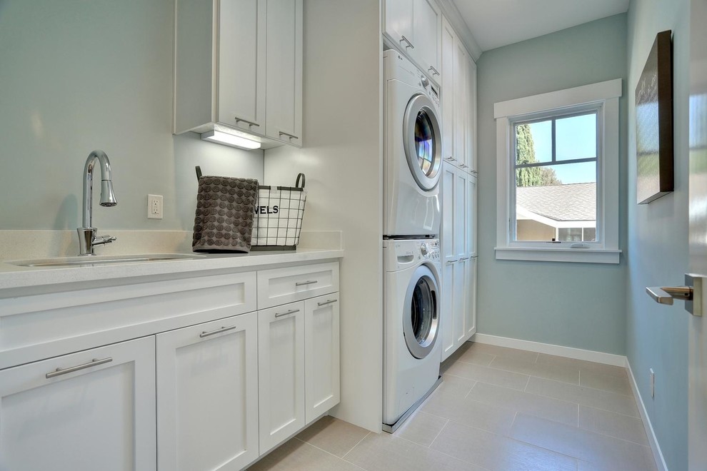 This is an example of a medium sized traditional single-wall separated utility room in San Francisco with a single-bowl sink, shaker cabinets, white cabinets, engineered stone countertops, blue walls, porcelain flooring and a stacked washer and dryer.