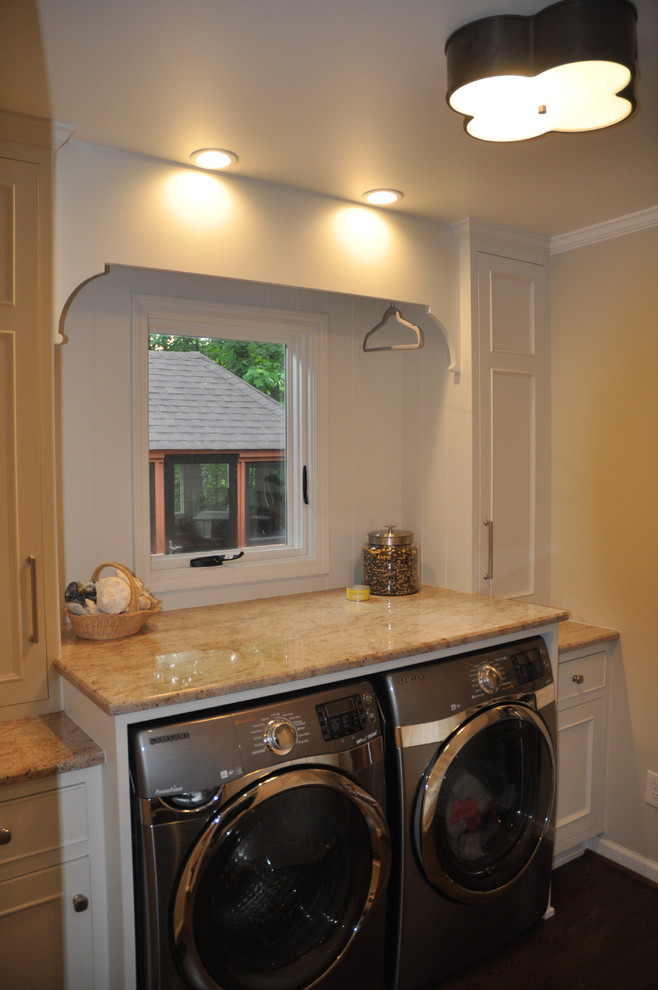 Bild på en mellanstor funkis linjär tvättstuga enbart för tvätt, med släta luckor, vita skåp, granitbänkskiva, beige väggar och en tvättmaskin och torktumlare bredvid varandra