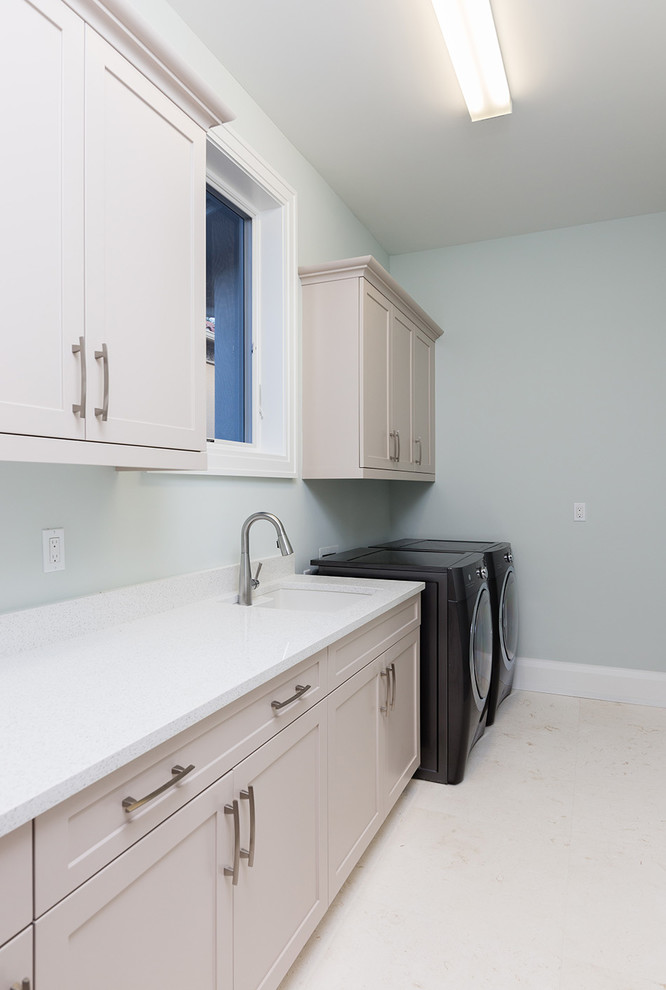 Medium sized contemporary single-wall separated utility room in Other with an utility sink, recessed-panel cabinets, beige cabinets, composite countertops, grey walls, ceramic flooring, a side by side washer and dryer and beige floors.