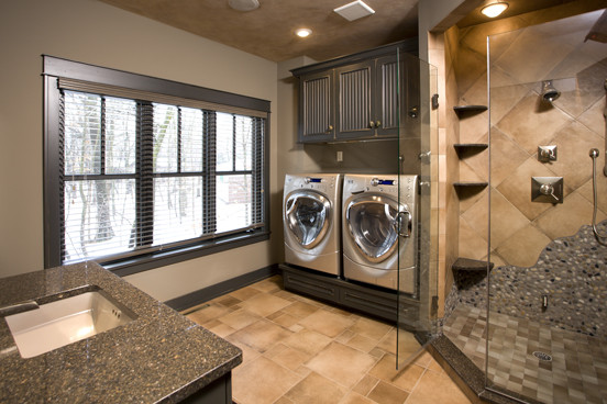 Foto di una lavanderia multiuso tradizionale di medie dimensioni con lavello sottopiano, ante con riquadro incassato, ante in legno bruno, pareti beige e lavatrice e asciugatrice affiancate