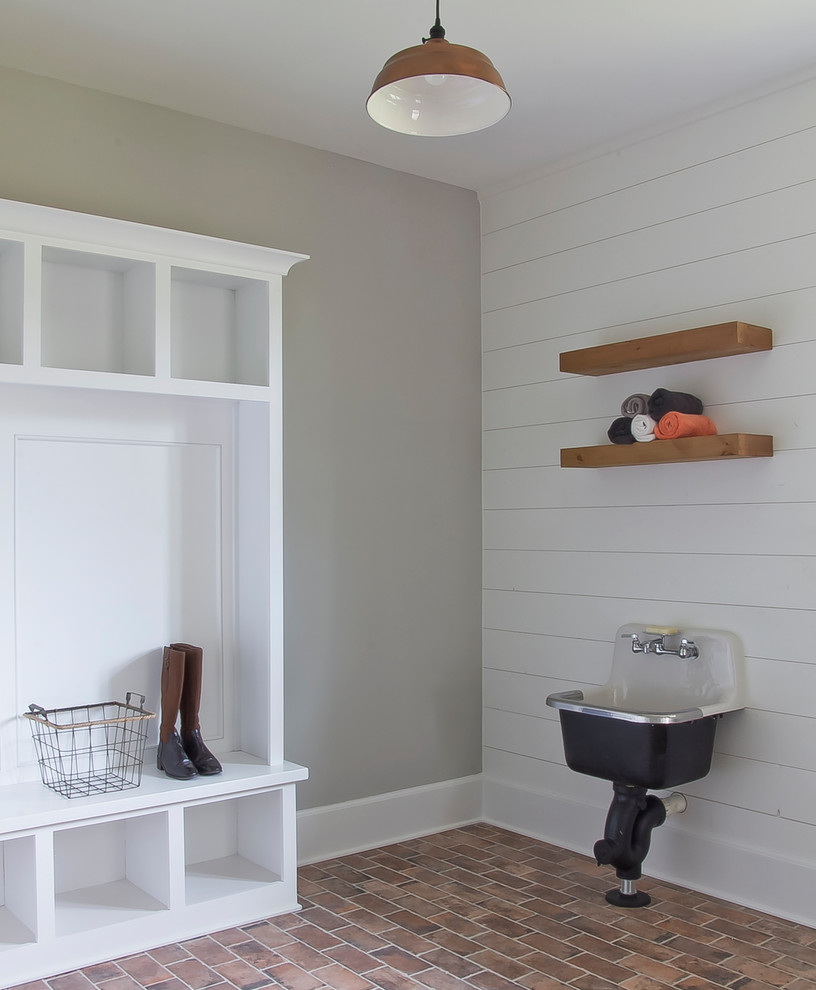 Photo of a medium sized country utility room in Atlanta with open cabinets, white cabinets, grey walls, brick flooring, red floors and an utility sink.