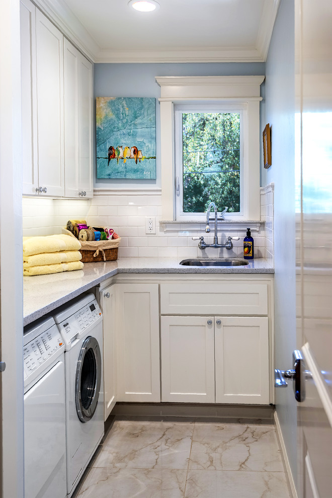 Example of a classic ceramic tile laundry room design in San Francisco with an undermount sink, white cabinets, marble countertops, blue walls and a side-by-side washer/dryer