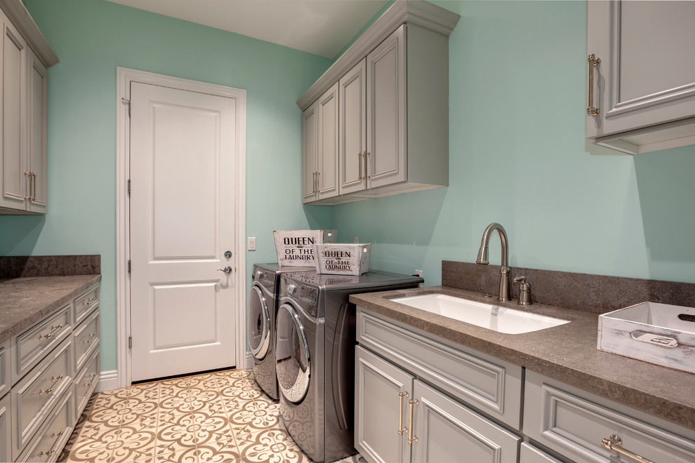 Foto di una grande lavanderia classica con lavello sottopiano, ante con riquadro incassato, ante grigie, pareti blu e lavatrice e asciugatrice affiancate