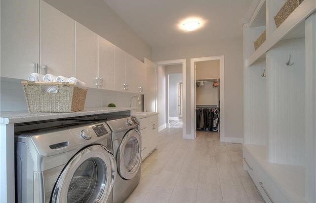 Idee per una grande sala lavanderia moderna con ante lisce, ante bianche, top in laminato, pareti beige, pavimento con piastrelle in ceramica, lavatrice e asciugatrice affiancate, pavimento beige e top beige
