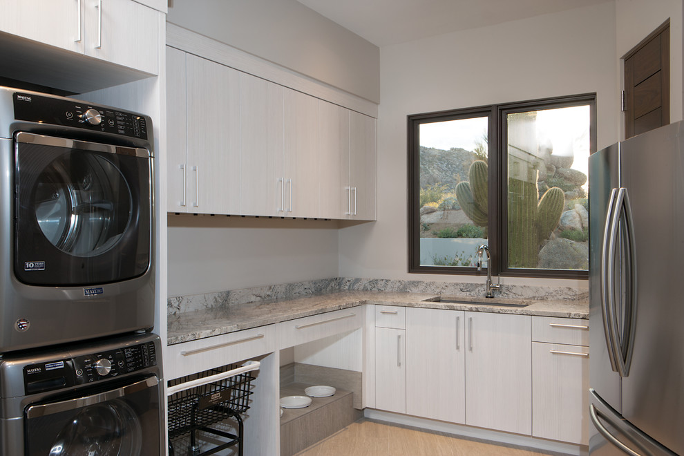 Exempel på ett mellanstort klassiskt grå u-format grått grovkök, med en undermonterad diskho, släta luckor, grå skåp, granitbänkskiva, vita väggar, klinkergolv i porslin, en tvättpelare och beiget golv