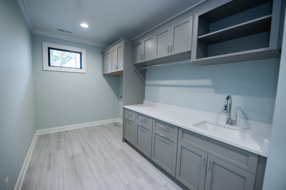 Trendy single-wall porcelain tile and gray floor dedicated laundry room photo in Raleigh with an utility sink, shaker cabinets, gray cabinets, quartz countertops, green walls, a side-by-side washer/dryer and white countertops