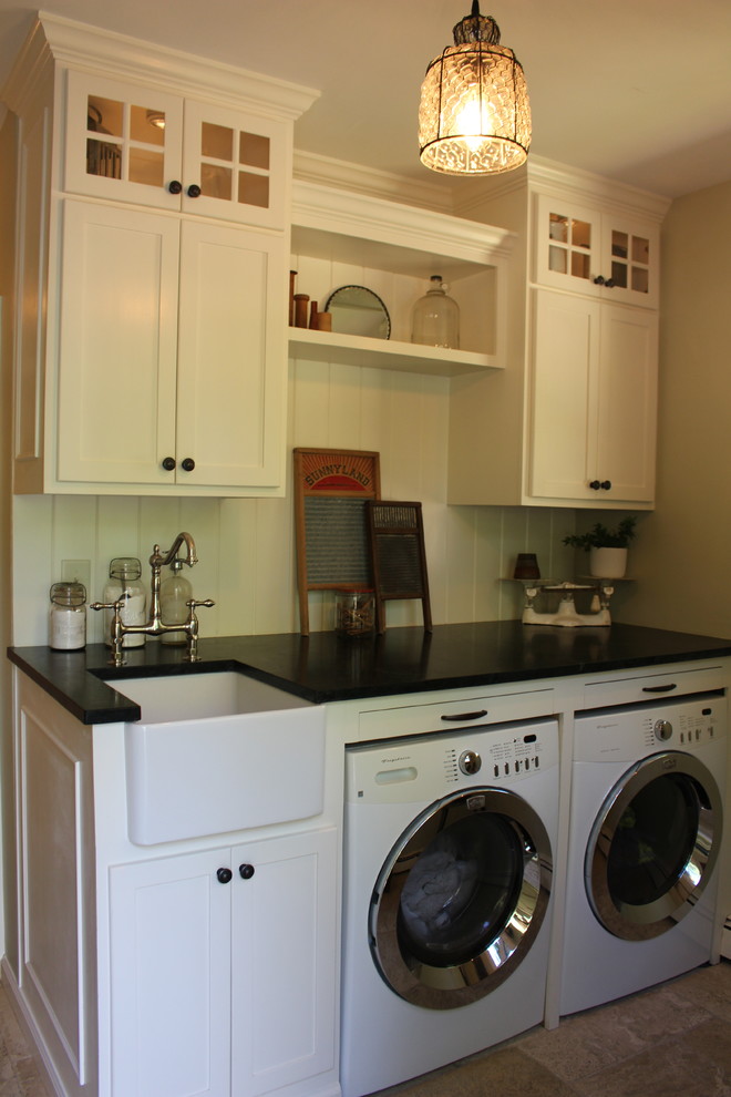 Design ideas for a small country utility room in Philadelphia with a belfast sink, recessed-panel cabinets, white cabinets, soapstone worktops, green walls, travertine flooring, a side by side washer and dryer and beige floors.